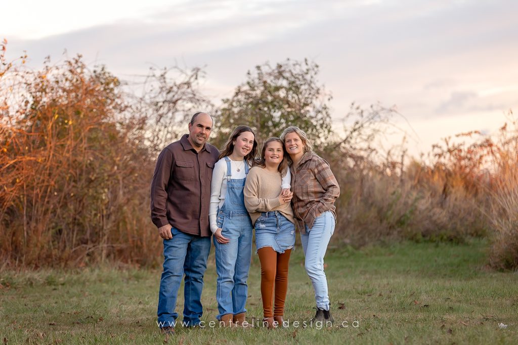 Family of four with long grass in the background.