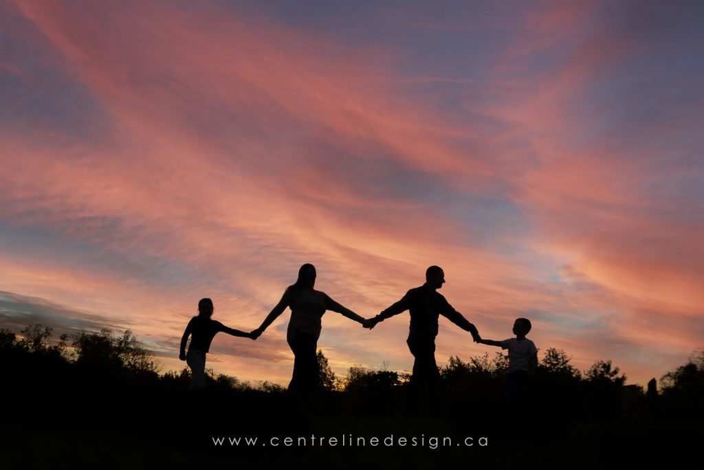 A silhouette of family walking with pink skies.
